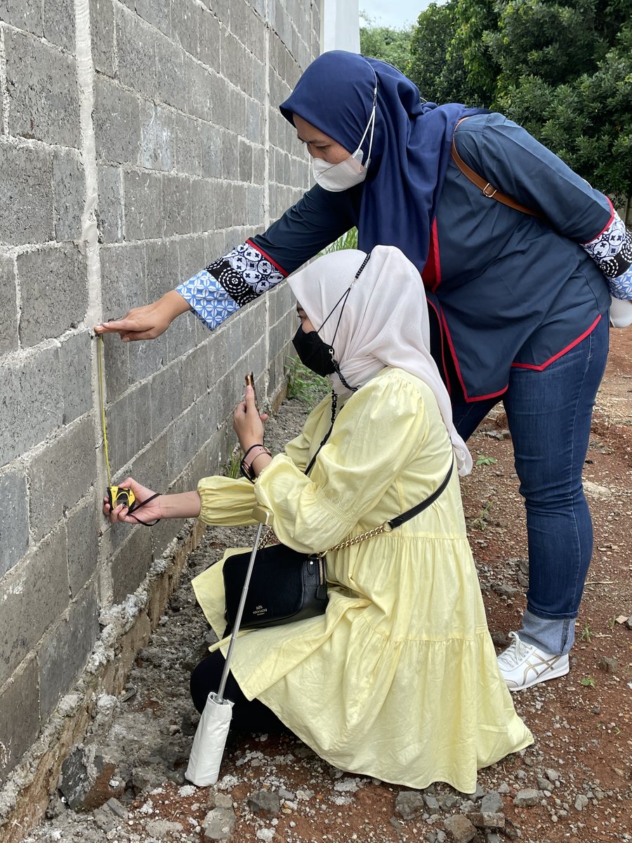 Two women measuring a block wall on a construction site